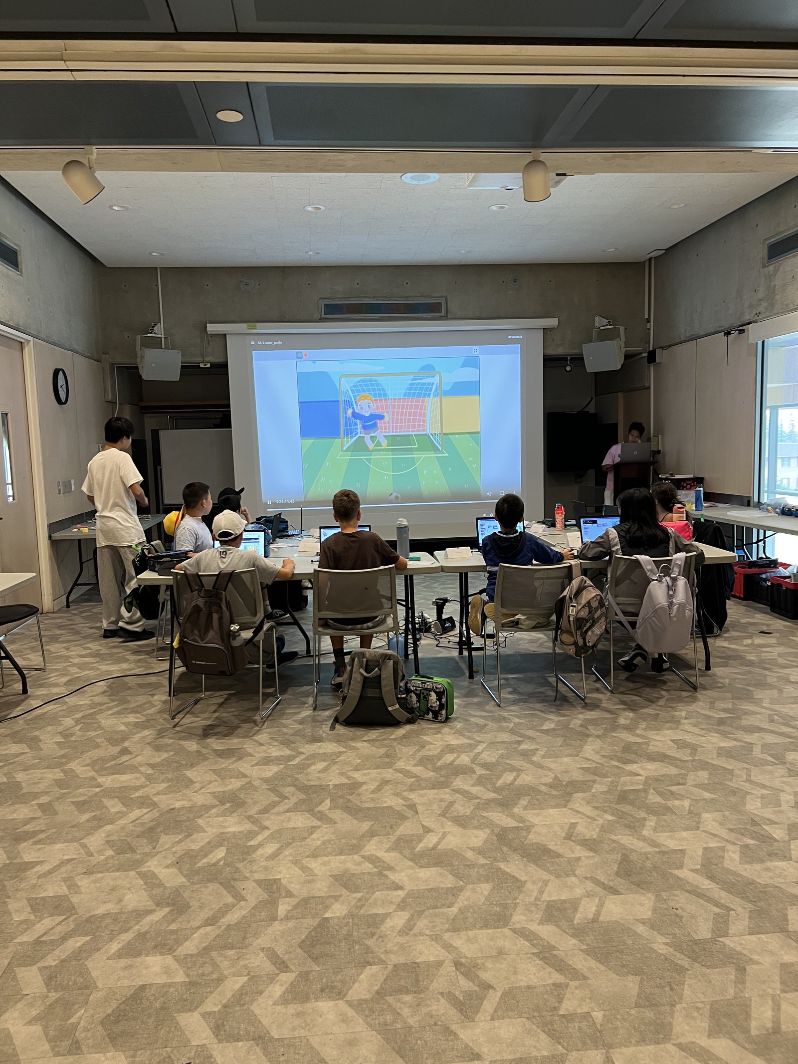 Projector lesson with students coding on laptops