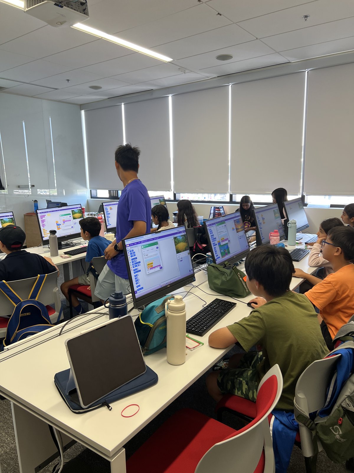Students coding on desktop computers with Scratch on screen