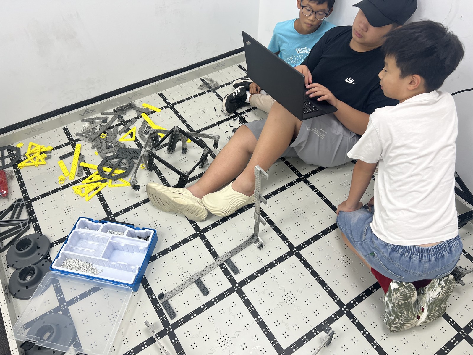 Students programming a VEX robot together on a laptop